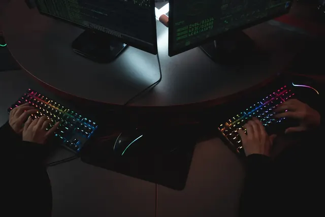 Kädet kirjoittavat RGB-näppäimistöillä pimeässä pelihuoneessa