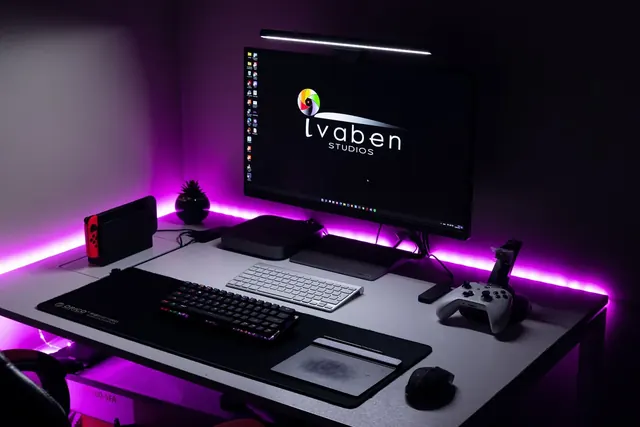 Violetein LED-valoin valaistu pelipöytä ja tietokone
